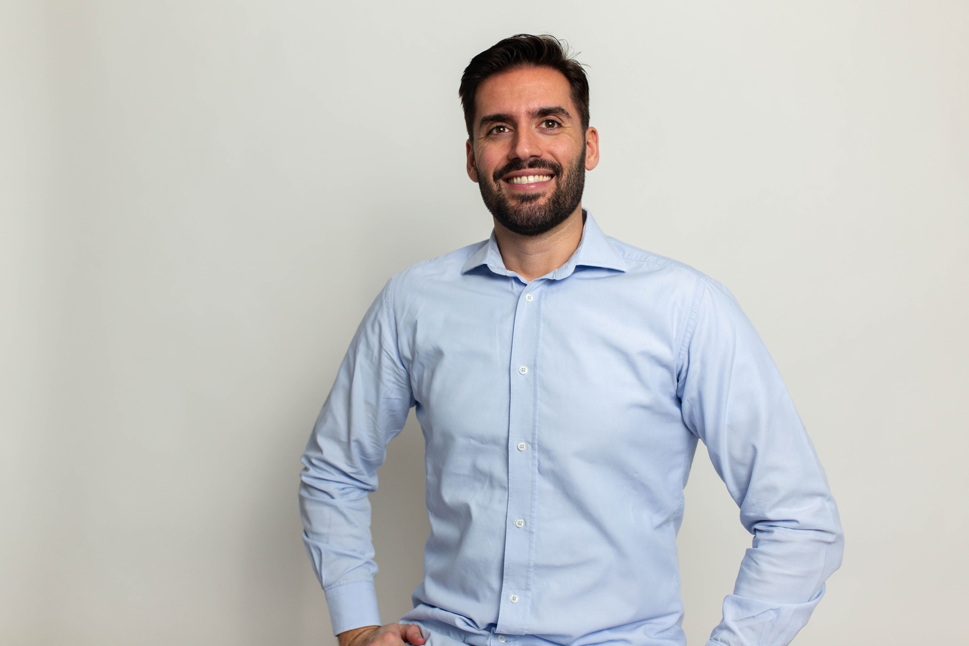 Young handsome business man dressed in casual denim shirt with smartwatch on wrist, isolated on gray background